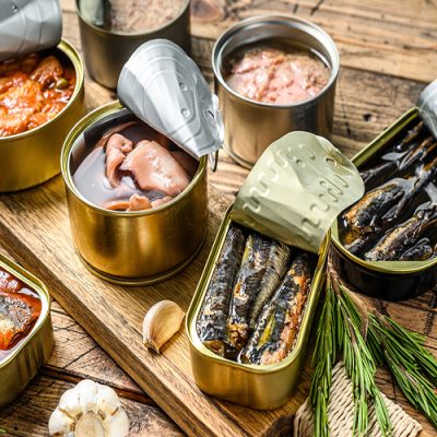 Various canned  fish and seafood in a metal cans. Wooden background. Top view.